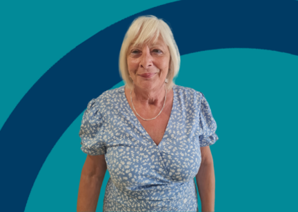 Lady in blue and white flower dress standing in front of a white background 