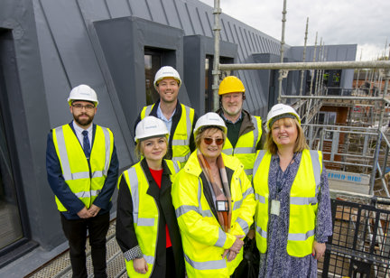 Colleagues and partners smiling, standing on the roof of a development