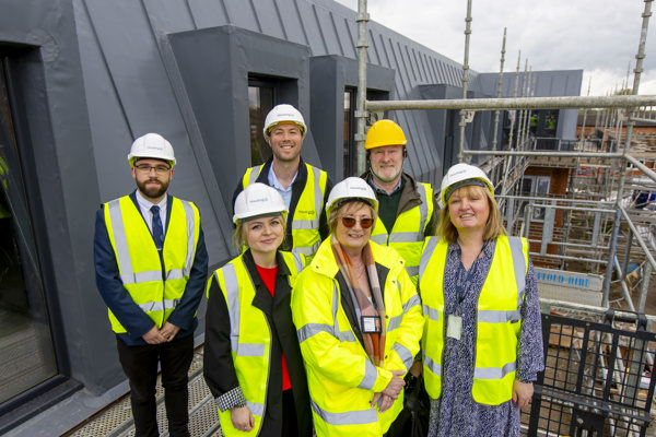 Colleagues and partners smiling, standing on the roof of a development
