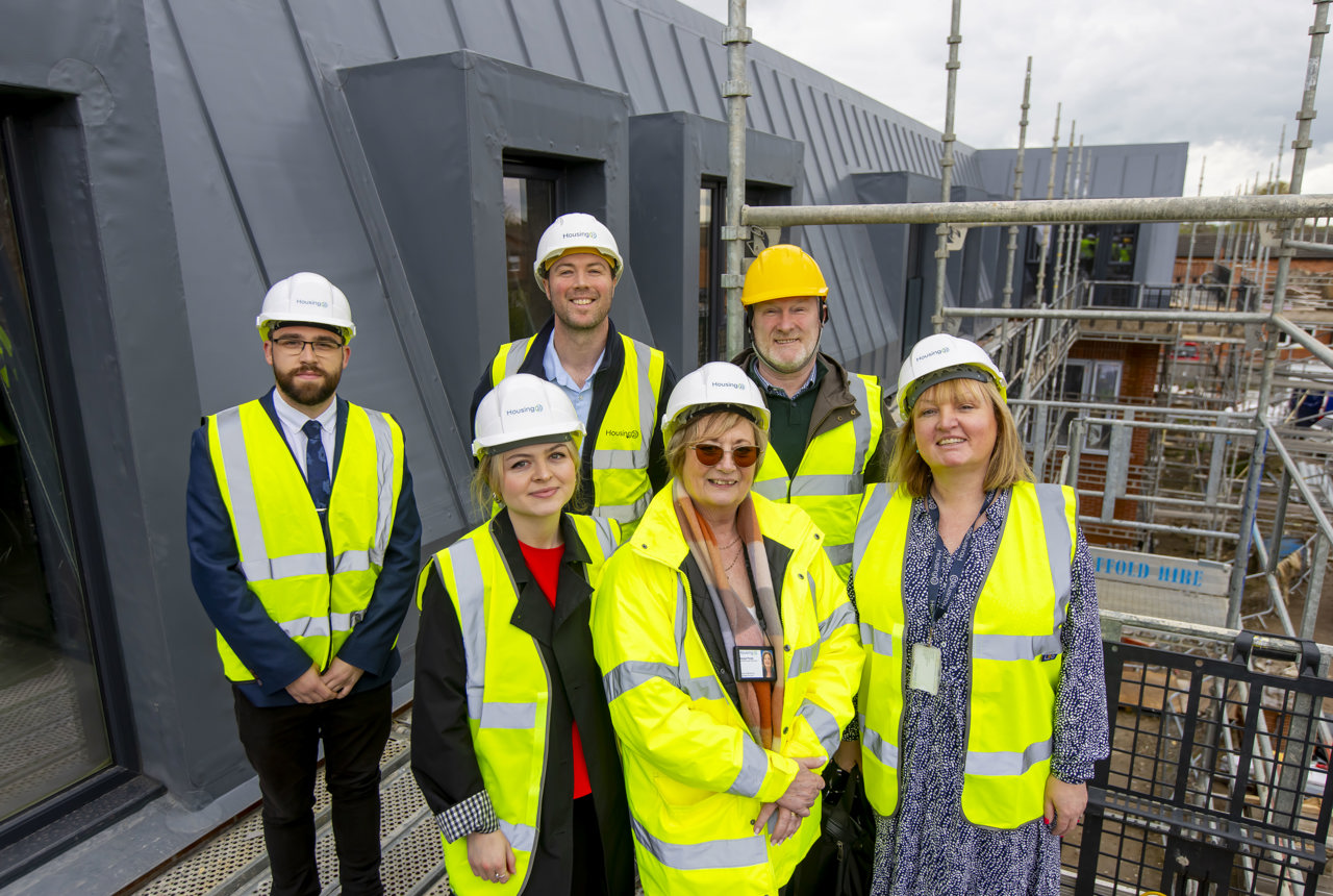 Colleagues and partners smiling, standing on the roof of a development
