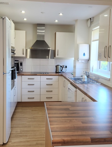 A communal kitchen, modern wooden work surfaces, and clean white cupboards 