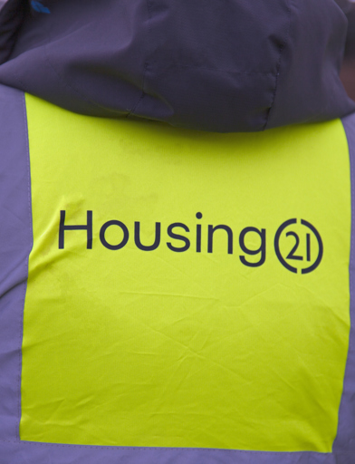 A close up of the back of a high vis jacket which says Housing 21  