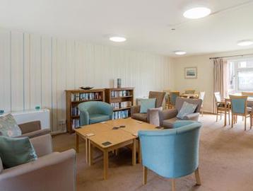 Residents' lounge with soft seating and coffee tables, and a selection of books on book shelves