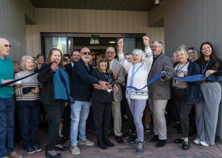 A group of residents, Housing 21 colleagues, celebrating as the ribbon is being cut