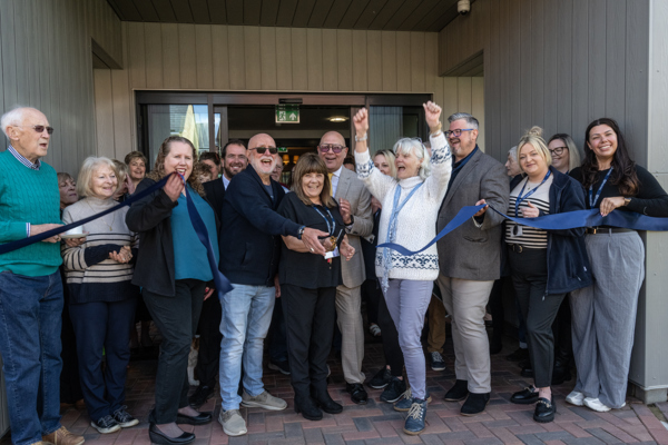 A group of residents, Housing 21 colleagues, celebrating as the ribbon is being cut