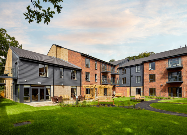 The exterior of a three-storey building surrounded by a lawn, outdoor seating and patio