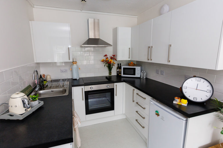 A modern kitchen with white walls and cupboards and black countertops